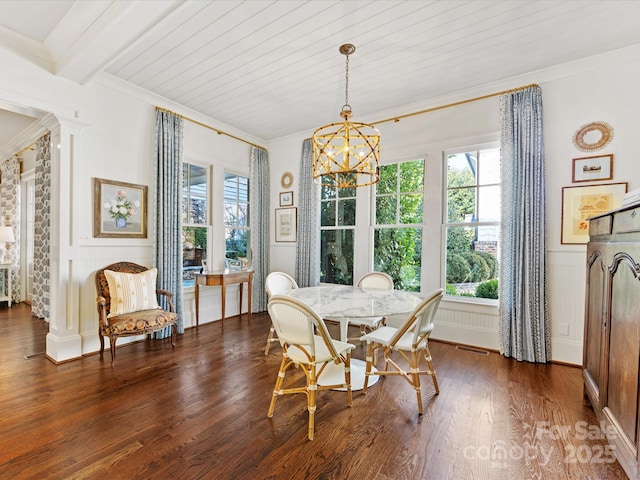 dining area featuring visible vents, ornamental molding, wood finished floors, a decorative wall, and a chandelier