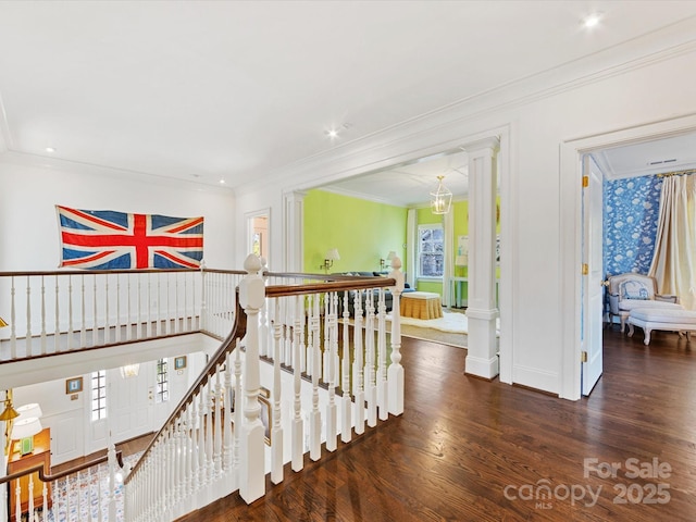 hallway featuring ornamental molding, wood finished floors, a wealth of natural light, and an upstairs landing