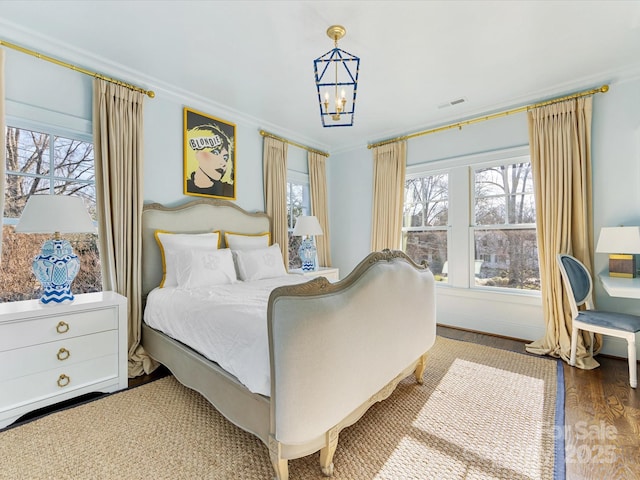 bedroom featuring wood finished floors, ornamental molding, a chandelier, and visible vents