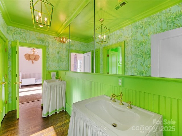 bathroom featuring wallpapered walls, visible vents, wood finished floors, and a wainscoted wall