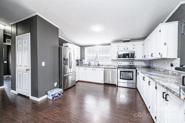 kitchen with crown molding, appliances with stainless steel finishes, white cabinets, and light stone counters