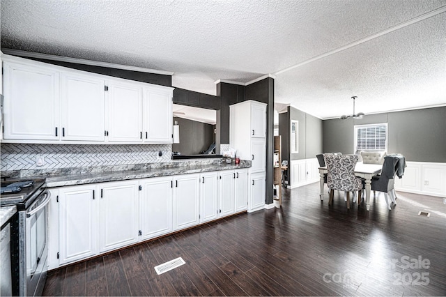 kitchen featuring lofted ceiling, dark wood-type flooring, hanging light fixtures, white cabinets, and stainless steel electric range oven