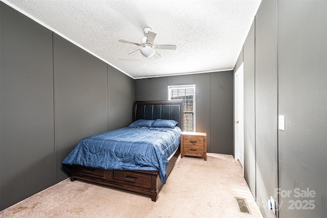 carpeted bedroom with ceiling fan and a textured ceiling