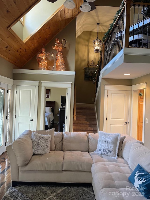 living room with dark wood-type flooring, a skylight, high vaulted ceiling, and wooden ceiling