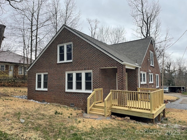 exterior space with crawl space, brick siding, roof with shingles, and a wooden deck