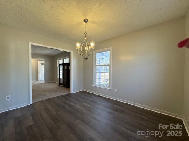 unfurnished dining area with a notable chandelier, dark hardwood / wood-style flooring, and a textured ceiling