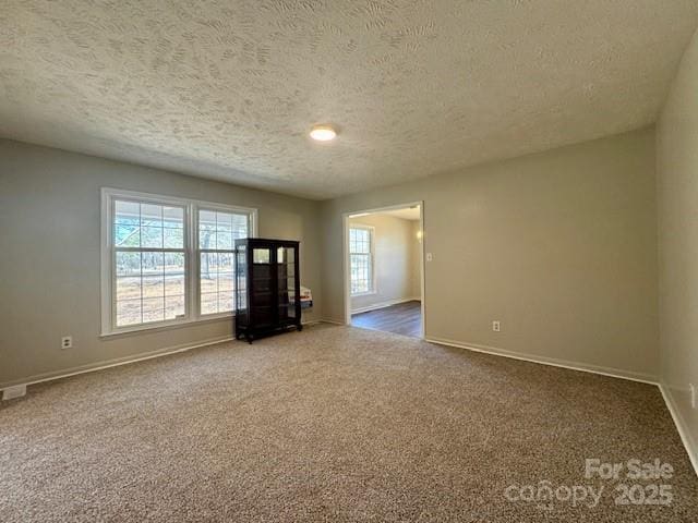 unfurnished living room with dark colored carpet and a textured ceiling