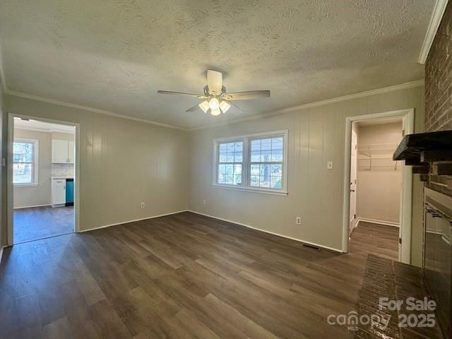 unfurnished living room with crown molding, dark wood-type flooring, a textured ceiling, and ceiling fan