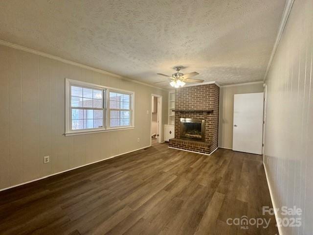 unfurnished living room featuring a brick fireplace, a textured ceiling, crown molding, dark wood-type flooring, and ceiling fan