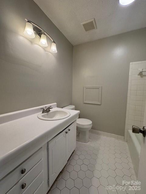 bathroom with vanity, tile patterned flooring, toilet, and a textured ceiling