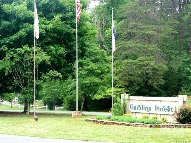 community sign with a forest view and a yard