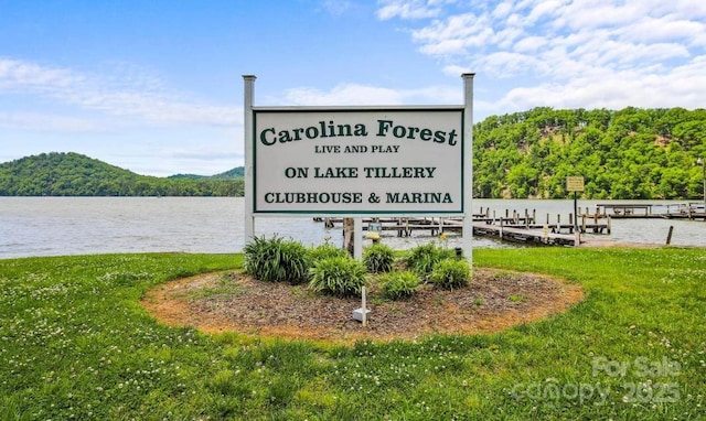 view of community featuring a water view, a lawn, and a dock