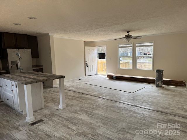 interior space with visible vents, a textured ceiling, ceiling fan, and stainless steel refrigerator with ice dispenser