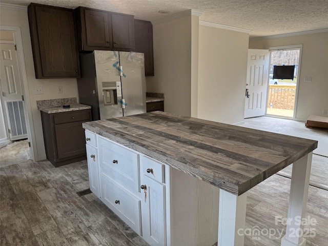 kitchen featuring visible vents, stainless steel fridge with ice dispenser, ornamental molding, wood finished floors, and a textured ceiling