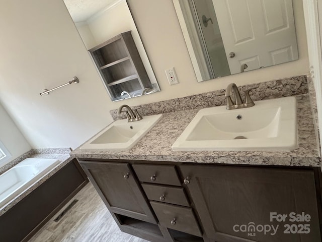 full bath with double vanity, a bathing tub, visible vents, and a sink
