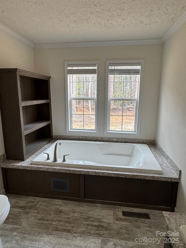 full bathroom with a garden tub, crown molding, visible vents, and a textured ceiling