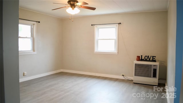 empty room featuring heating unit, hardwood / wood-style floors, ornamental molding, and ceiling fan