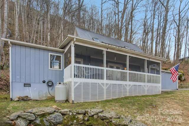 rear view of house featuring a sunroom and a yard