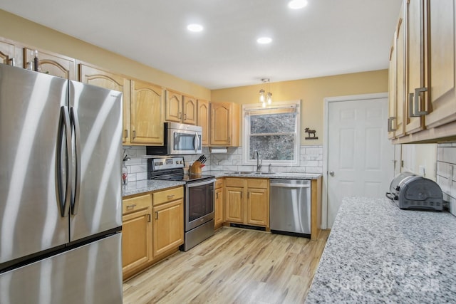 kitchen featuring appliances with stainless steel finishes, tasteful backsplash, sink, hanging light fixtures, and light hardwood / wood-style flooring