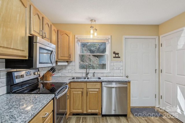 kitchen featuring sink, hanging light fixtures, light hardwood / wood-style flooring, appliances with stainless steel finishes, and decorative backsplash