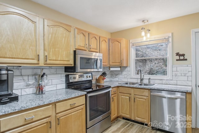 kitchen featuring sink, hanging light fixtures, light stone counters, stainless steel appliances, and light brown cabinets