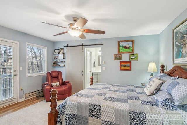 bedroom with hardwood / wood-style flooring, a barn door, a baseboard heating unit, and ceiling fan