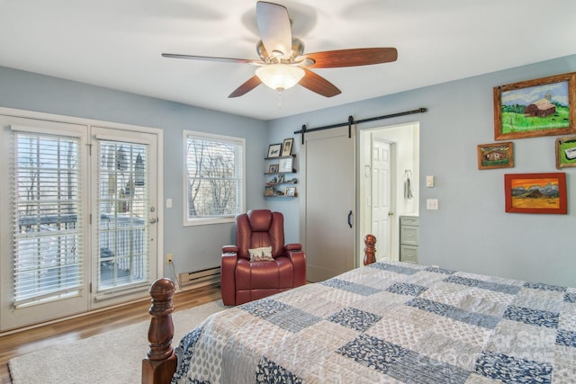 bedroom featuring light wood-type flooring, baseboard heating, access to outside, ceiling fan, and a barn door