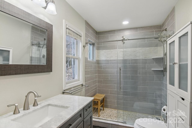 bathroom with vanity, a shower with door, and toilet