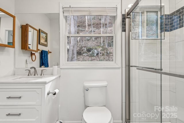 bathroom featuring walk in shower, vanity, toilet, and a wealth of natural light