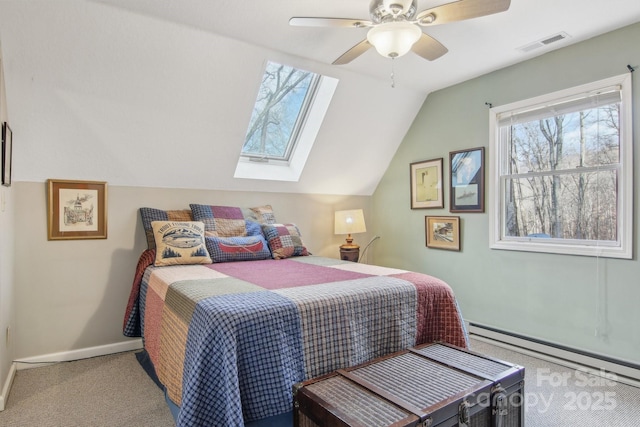 bedroom with ceiling fan, a baseboard radiator, vaulted ceiling with skylight, and carpet floors