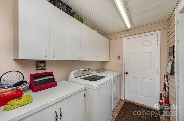 clothes washing area with cabinets and washer and dryer