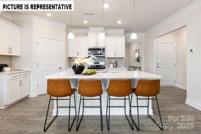 kitchen with stainless steel appliances, white cabinetry, and a kitchen island with sink