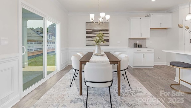 108 Sari St, Troutman, NC 28166 - dining space featuring a chandelier, crown molding, light wood finished floors, and a wainscoted wall