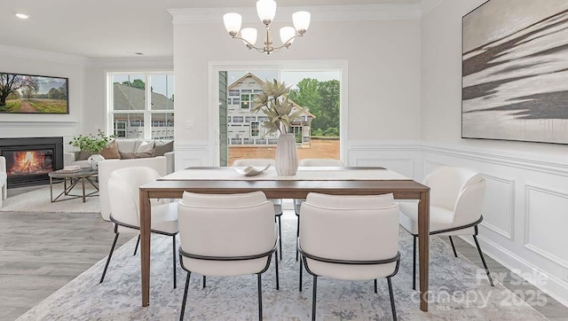 108 Sari St, Troutman, NC 28166 - dining space featuring a decorative wall, ornamental molding, a chandelier, a glass covered fireplace, and light wood finished floors