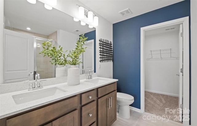 bathroom featuring toilet, vanity, and a shower with door