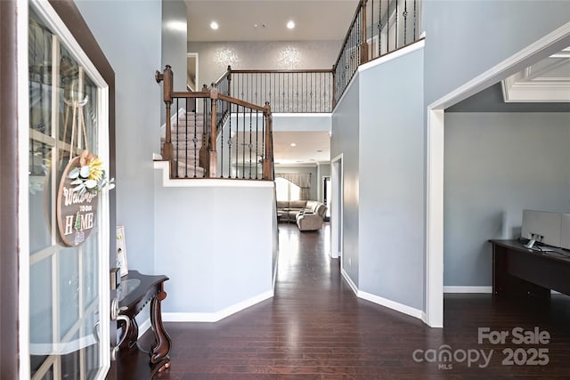 foyer entrance featuring baseboards, a towering ceiling, hardwood / wood-style flooring, stairs, and recessed lighting