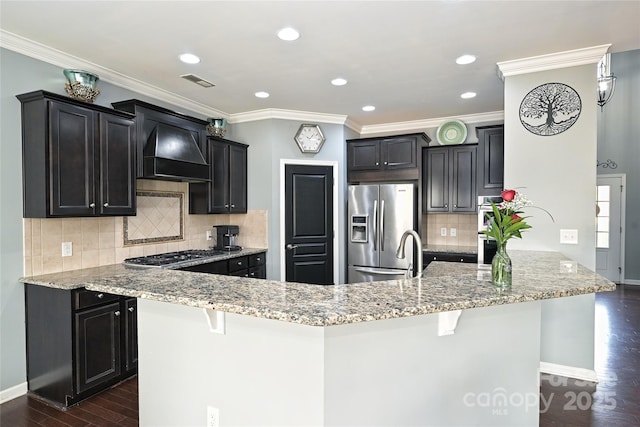 kitchen with light stone counters, stainless steel appliances, dark wood-type flooring, visible vents, and custom range hood