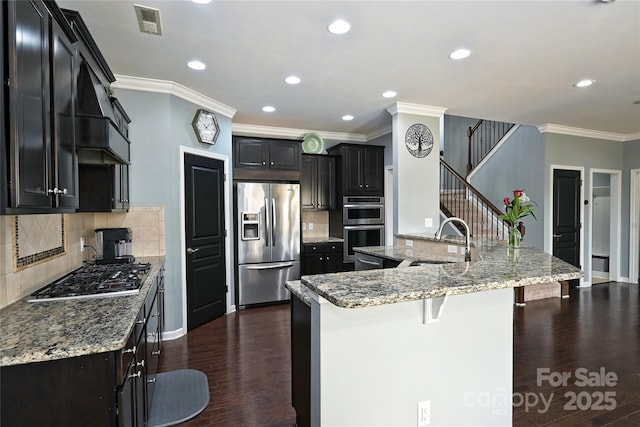 kitchen featuring appliances with stainless steel finishes, a sink, dark wood finished floors, and dark cabinetry