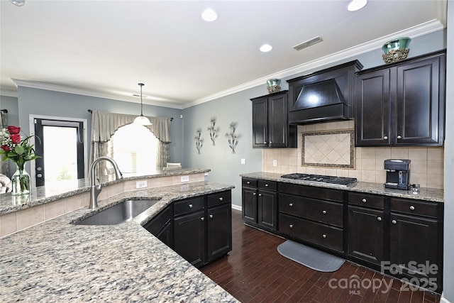 kitchen featuring stainless steel gas cooktop, visible vents, dark wood-type flooring, a sink, and premium range hood