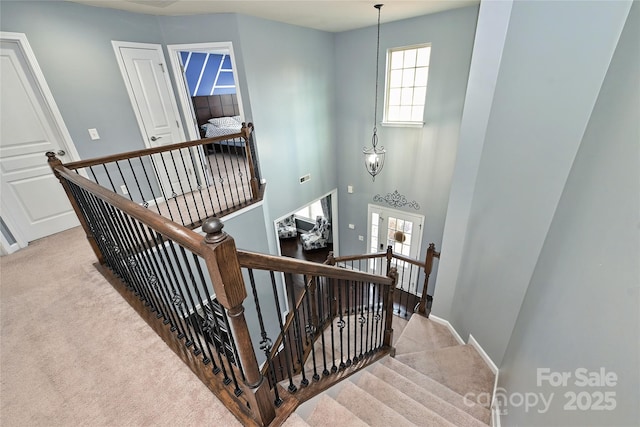 stairway featuring a towering ceiling, carpet, and baseboards