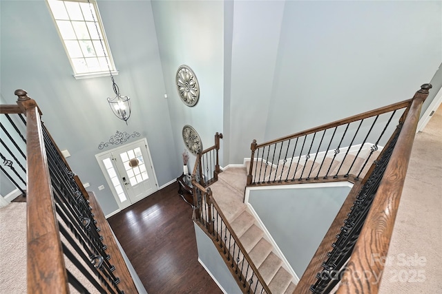 entryway featuring plenty of natural light, wood finished floors, a towering ceiling, and baseboards