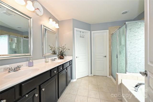 bathroom featuring double vanity, a shower stall, a sink, and tile patterned floors