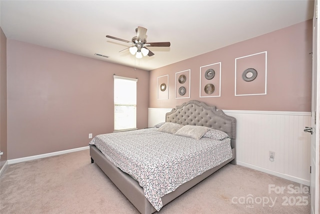 carpeted bedroom with baseboards, visible vents, a ceiling fan, and wainscoting