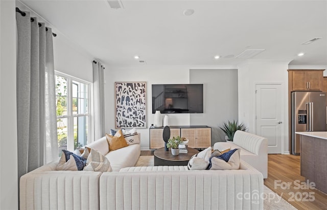 living room with light hardwood / wood-style floors and crown molding