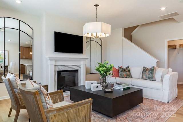 living room featuring a high end fireplace and light hardwood / wood-style flooring