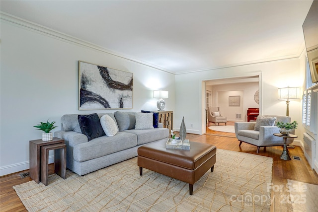 living room with crown molding and light hardwood / wood-style flooring