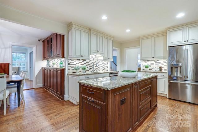 kitchen with a center island, high end fridge, sink, and light hardwood / wood-style flooring