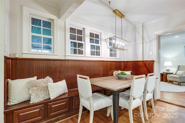 dining space with ornamental molding, wood-type flooring, and an inviting chandelier