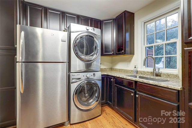 laundry area with stacked washer and clothes dryer, sink, light hardwood / wood-style floors, and plenty of natural light