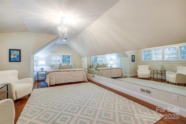 bedroom with lofted ceiling, a chandelier, and hardwood / wood-style floors